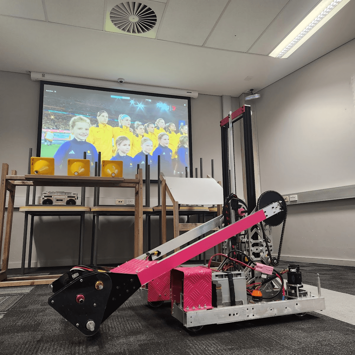 The 2023 robot with its arm raised in a classroom