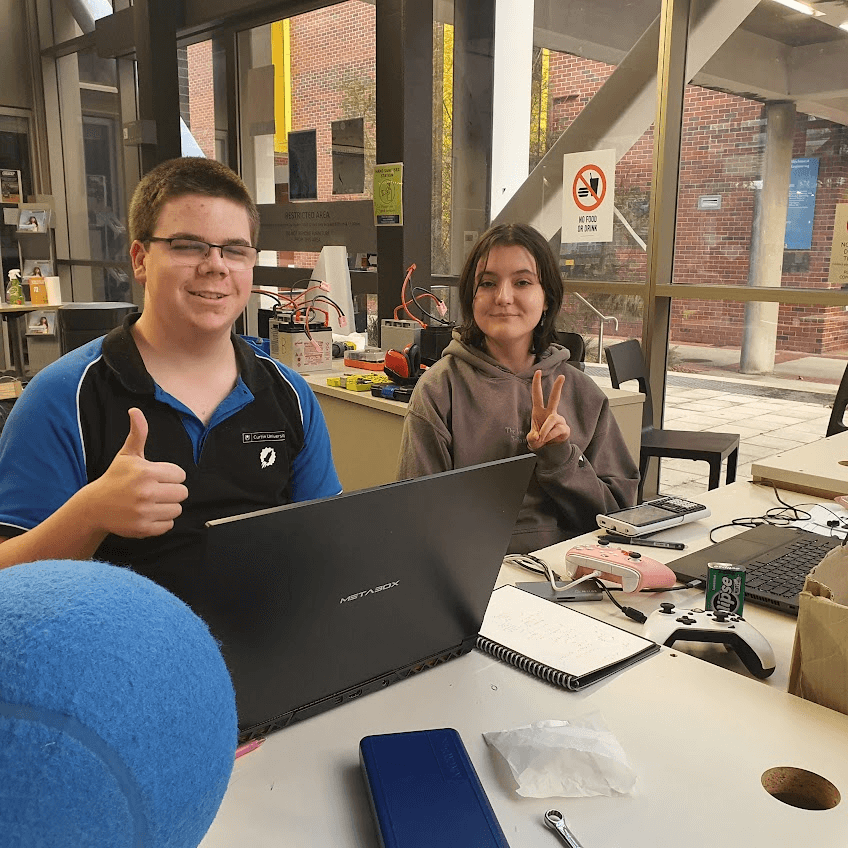 Two team members at a laptop giving a thumbs up