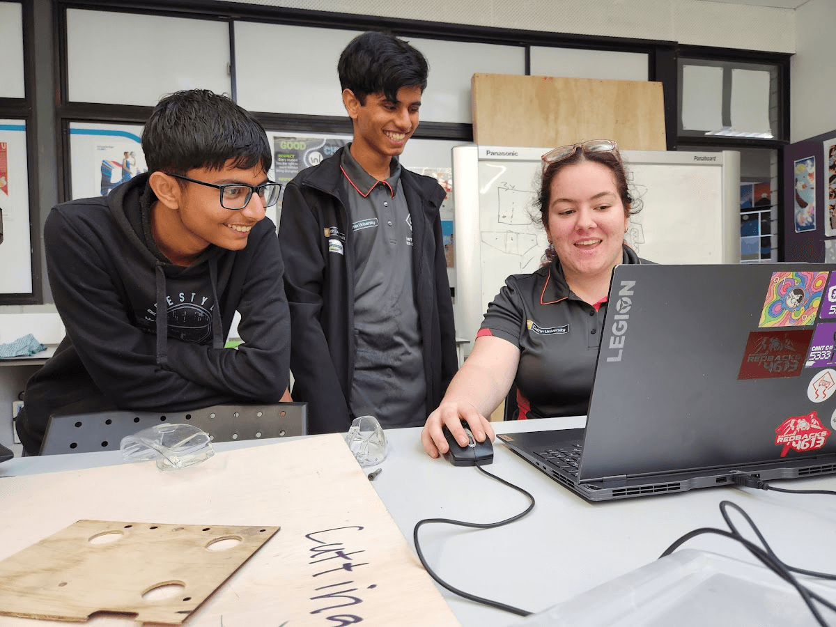 Three team members working at a laptop